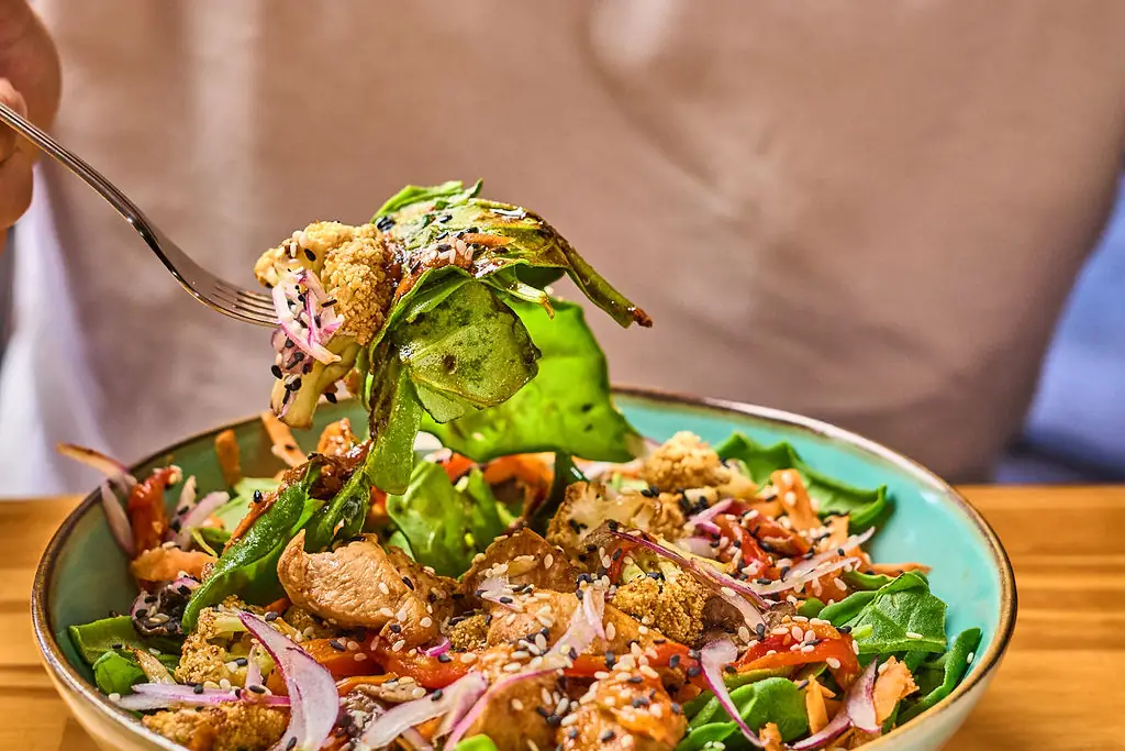 Persona comiendo una ensalada con tenedor en una mesa de Wö Kàpi