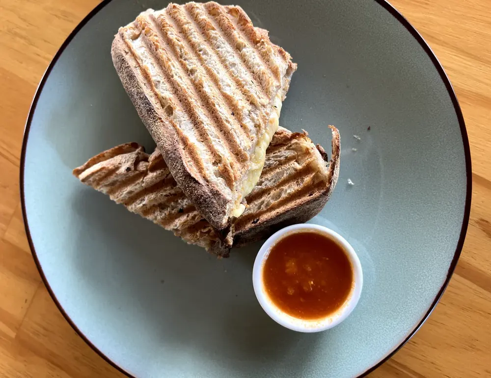Derretido de pan de masa madre prensado, cortado en dos triángulos, con un recipiente de salsa de tomate al lado