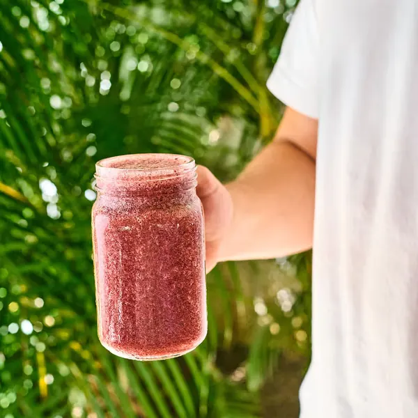 Batido en un frasco de vidrio, sostenido frente a las plantas