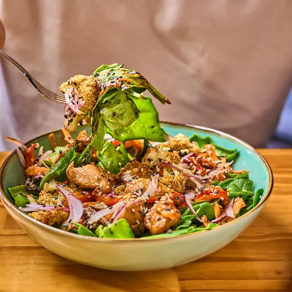 Bowl de almuerzo con pollo, hojas verdes y cebolla morada